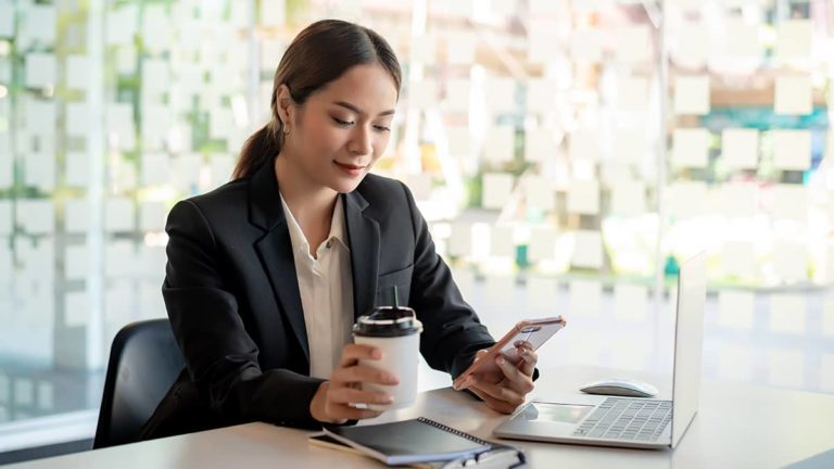 女商人一手拿着咖啡，一手拿着手机