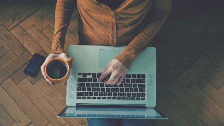 一个人在电脑上拿着一杯咖啡