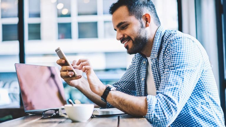 坐在书桌的商人看他的智能手机